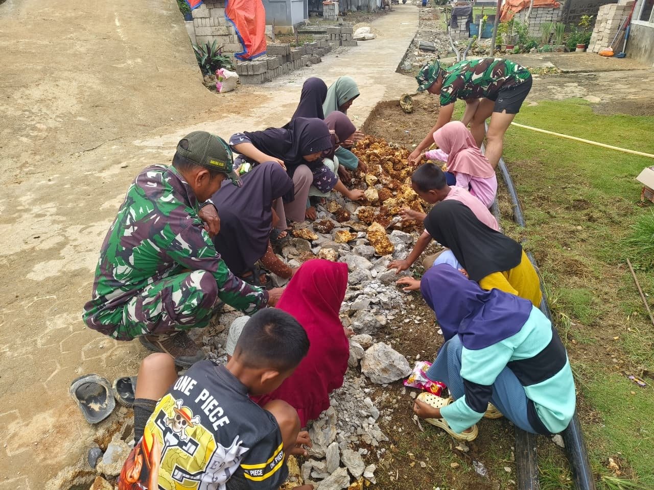 Hari Libur, Anak-anak SD Berinisiatif Bantu Satgas TMMD Meratakan Batu Rabat Beton