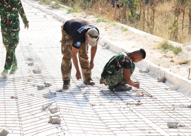 Ketelitian prajurit Satgas TMMD ke 129 dalam bahu-membahu memasang batu penahan di bawah rangkaian besi wiremesh sebelum tahap pengecoran jalan dimulai