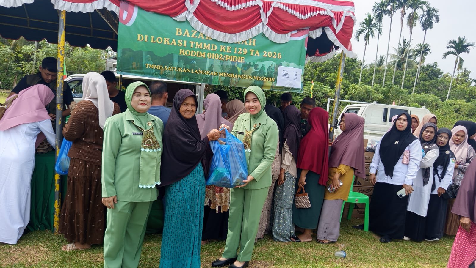 Ketua Persit KCK Cabang XIX Kodim 0102/Pidie dan Wakil Ketua Bhayangkari Polres Pidie Layani Warga di Bazar Murah TMMD ke-129