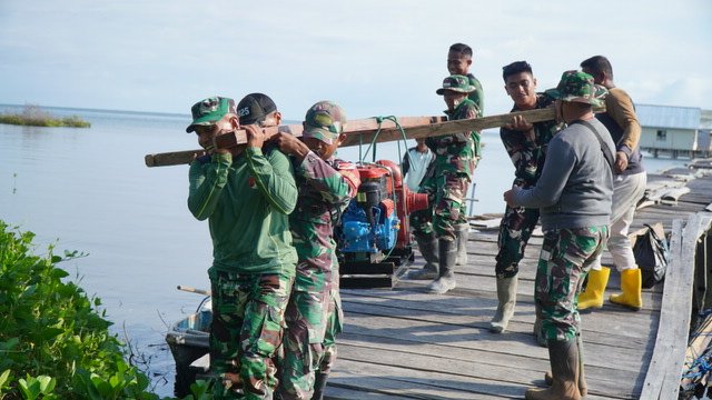 Satgas TMMD Bersama Masyarakat Gotong Royong Memikul Mesin Air untuk Program Manunggal Air