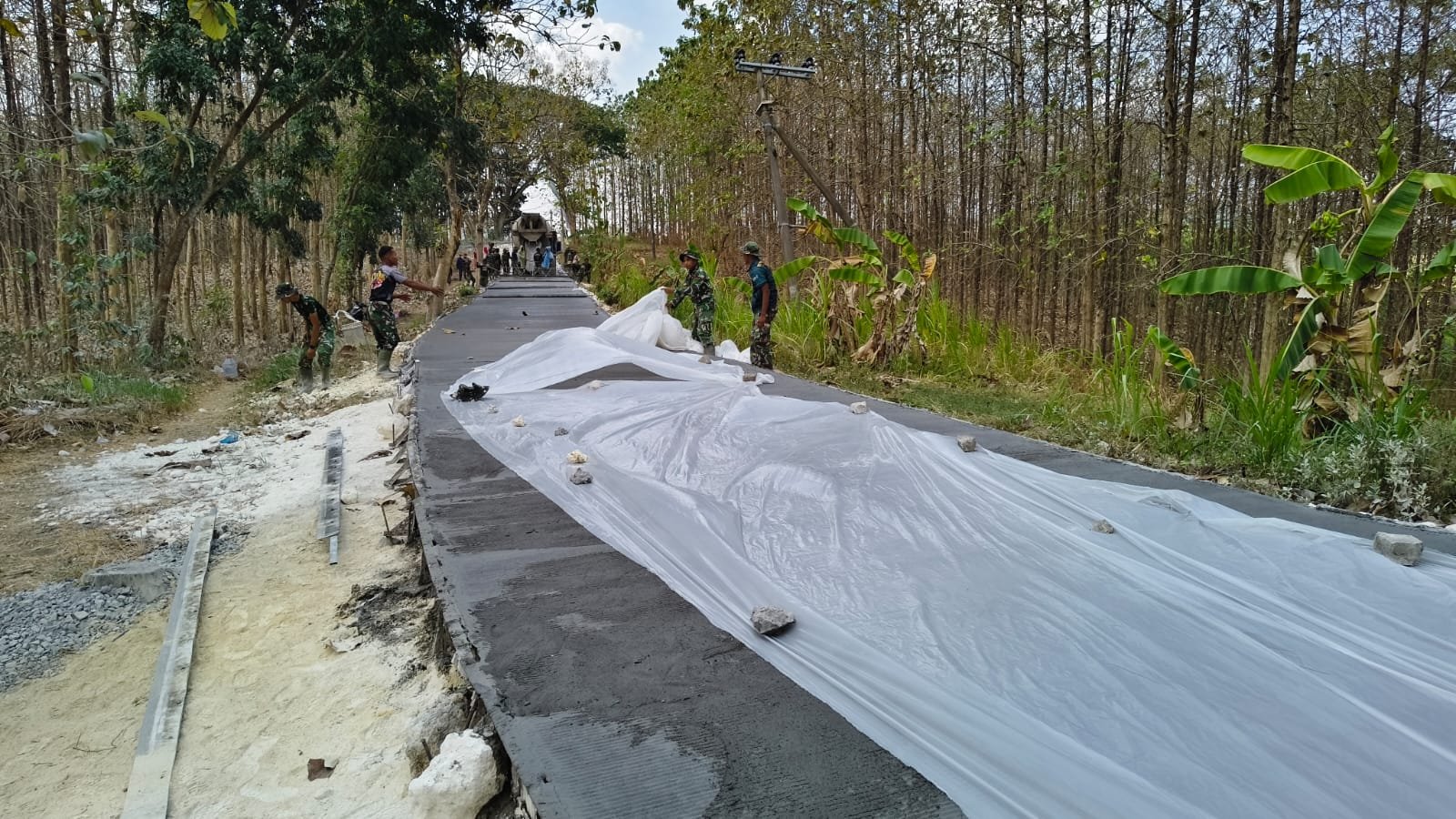 ​Jaga Kualitas Infrastruktur, Satgas TMMD 129 Kodim 0812/Lamongan Bentang Plastik Lindungi Hasil Cor Jalan dari Terik Matahari