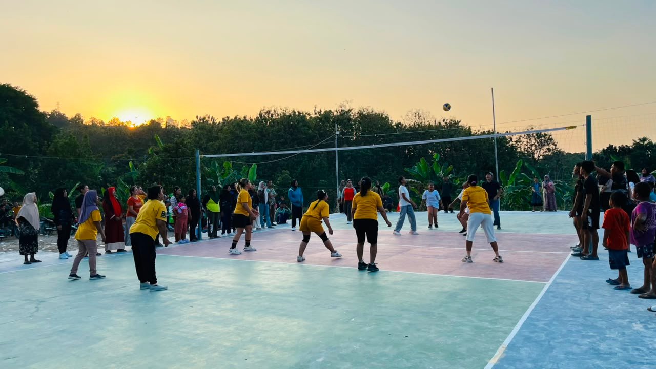 Pemandangan Sore nan Indah: Langit Cerah Iringi Emak-Emak dan Pemudi Asyik Bermain di Lapangan Voli Karya Satgas TMMD 129