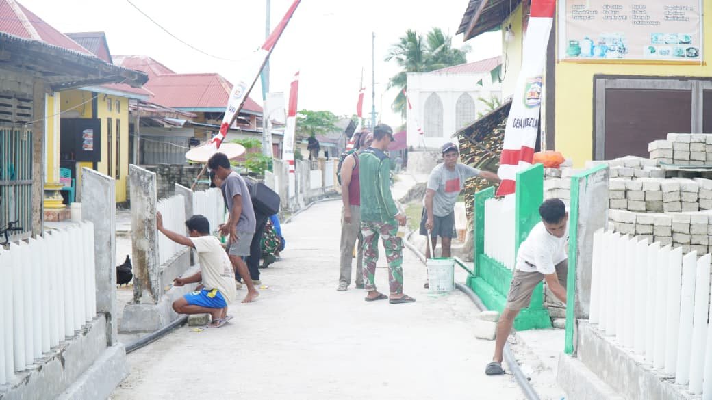 Satgas TMMD Bersama Masyarakat Laksanakan Pengecatan Pagar, Percantik Desa Umbele